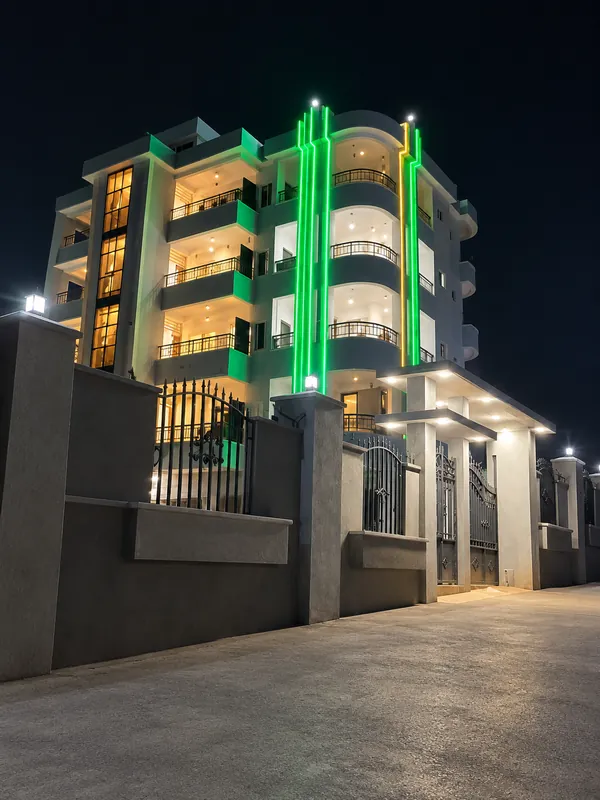 Night view of a building with green light strips and warmly lit balconies.
